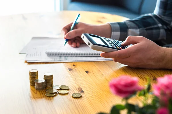 Person calculating a catering budget beside stacked coins